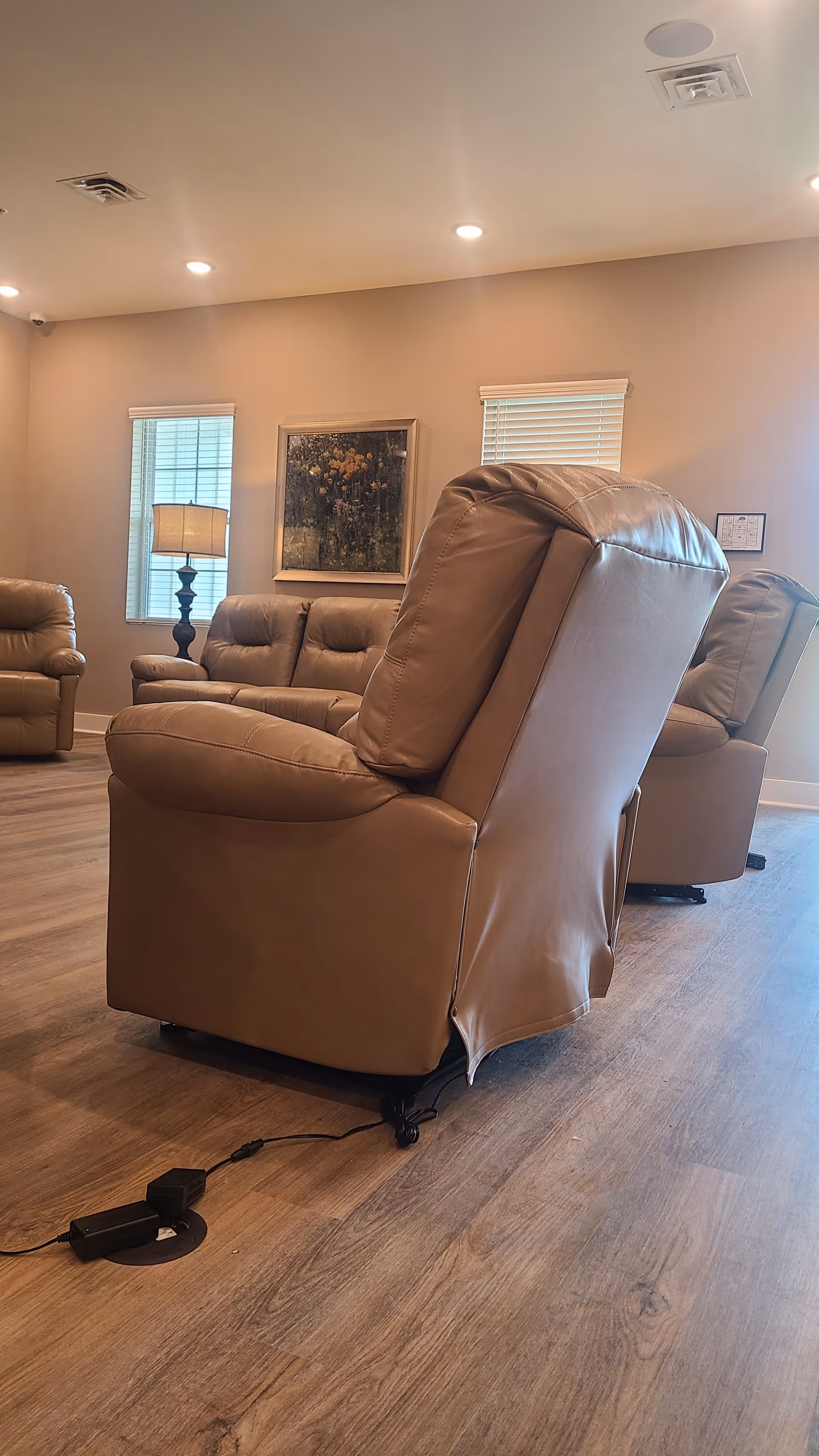 Leather recliners arranged in a cozy living room with a lamp and painting.