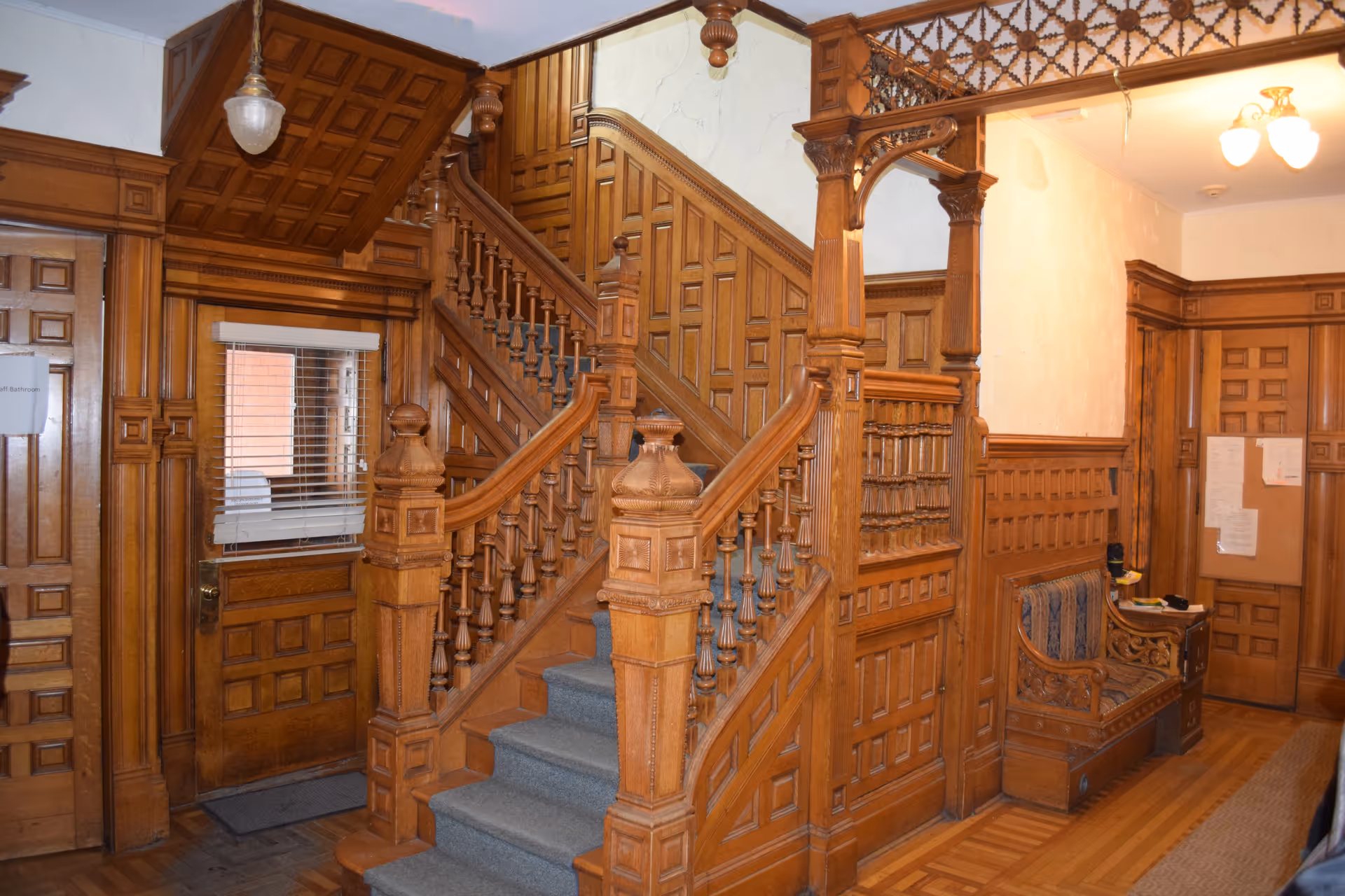 Ornate wooden staircase and paneled foyer inside Liberty Resources Maxwell House senior living facility.