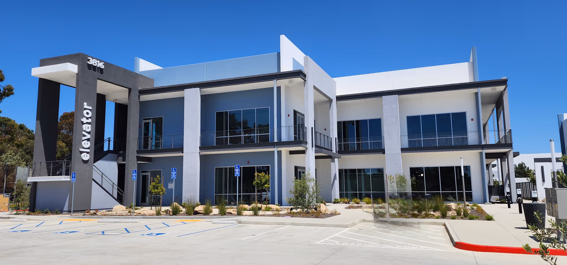 Modern two-story nursing facility exterior with balconies and an elevator tower.