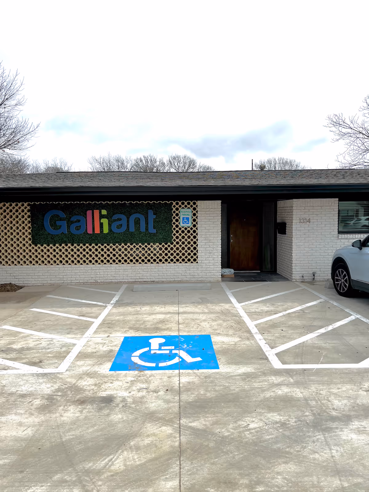 Front of a low-brick building with a lattice screen and blue handicap parking.