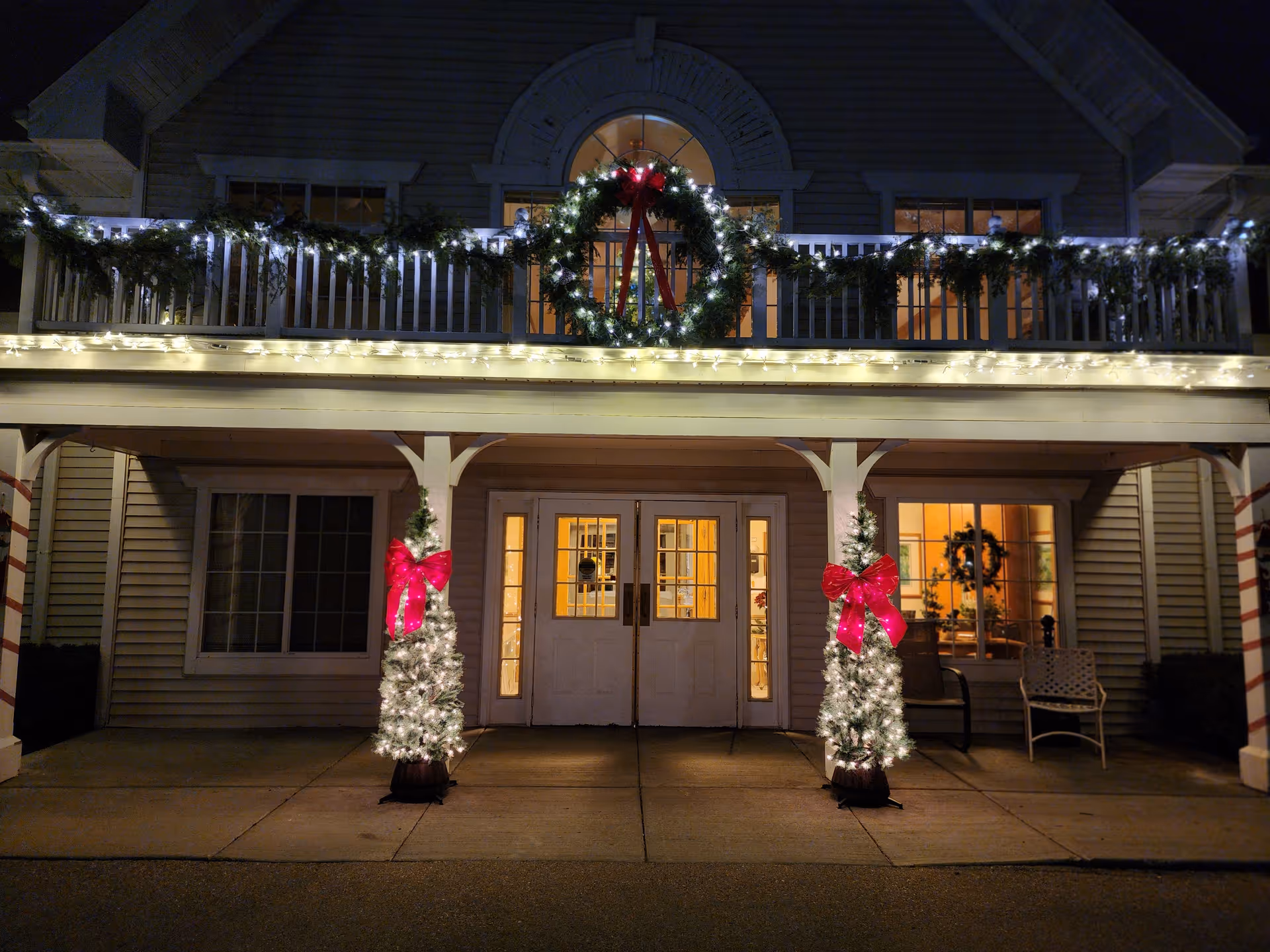 Front entrance of a senior living facility decorated with Christmas lights and wreaths.