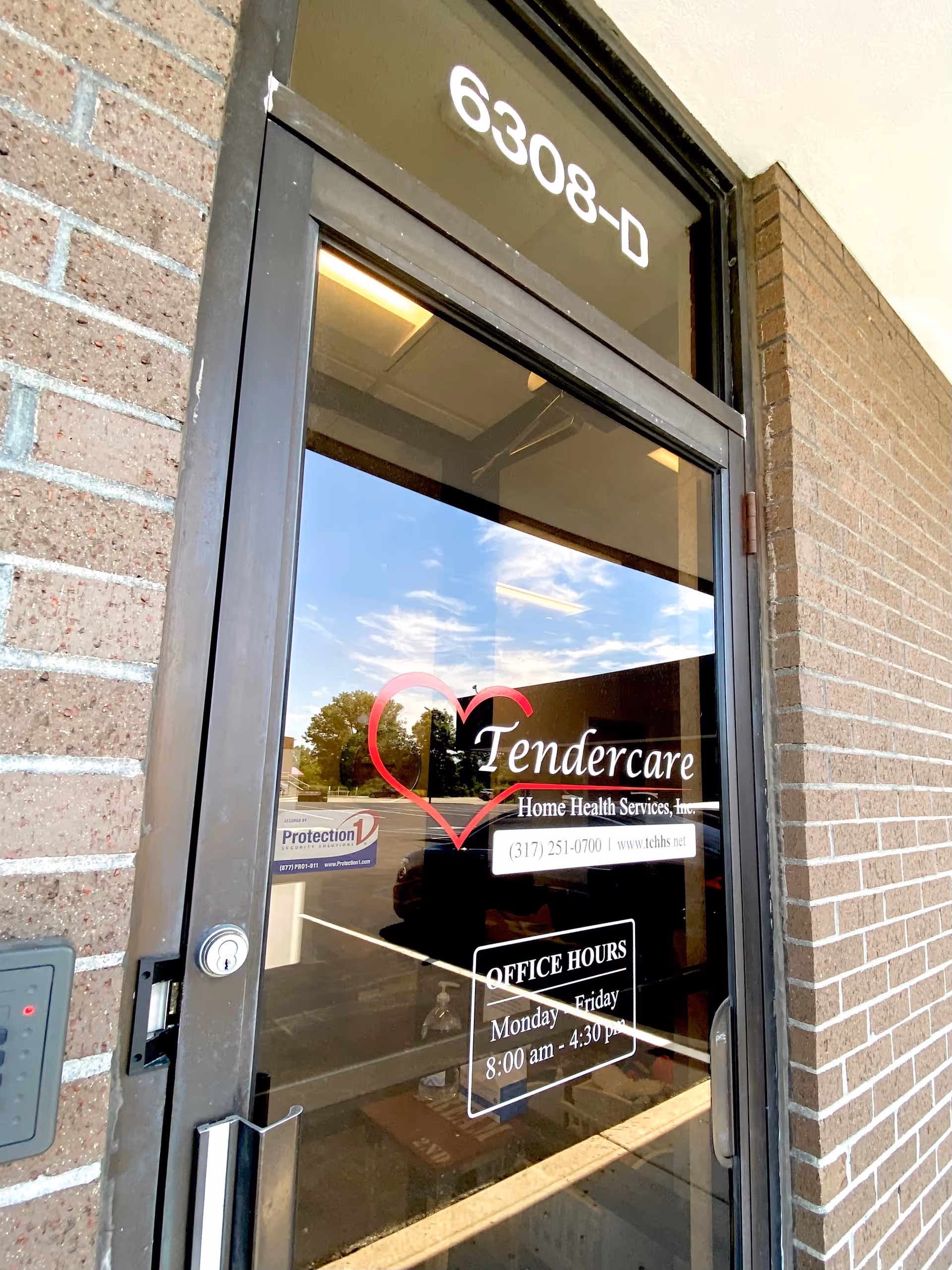 Glass entrance door with Tendercare logo on brick exterior wall and posted hours.