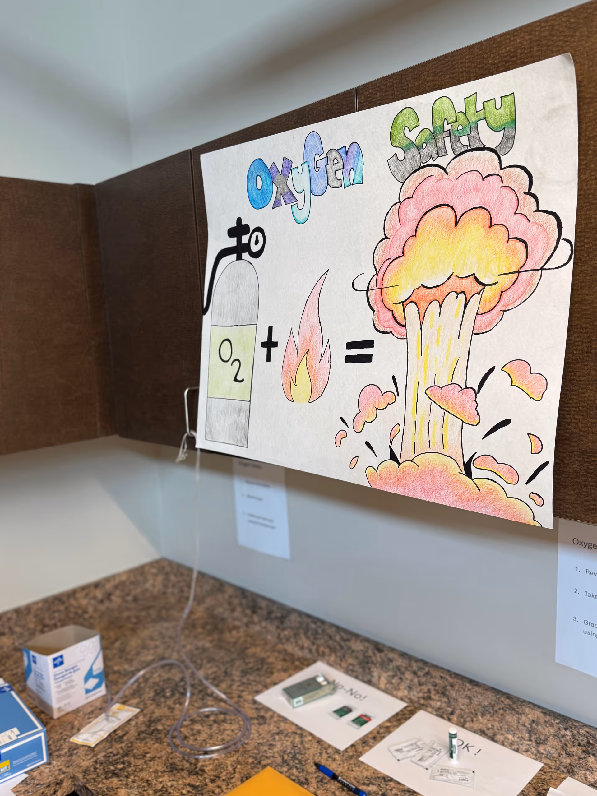 Colorful oxygen safety poster pinned to a wall above a countertop in a facility.