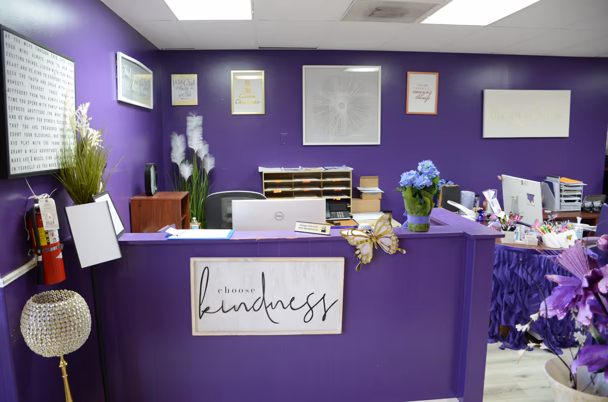 Purple reception desk in a senior care lobby with a 'choose kindness' sign and decor.