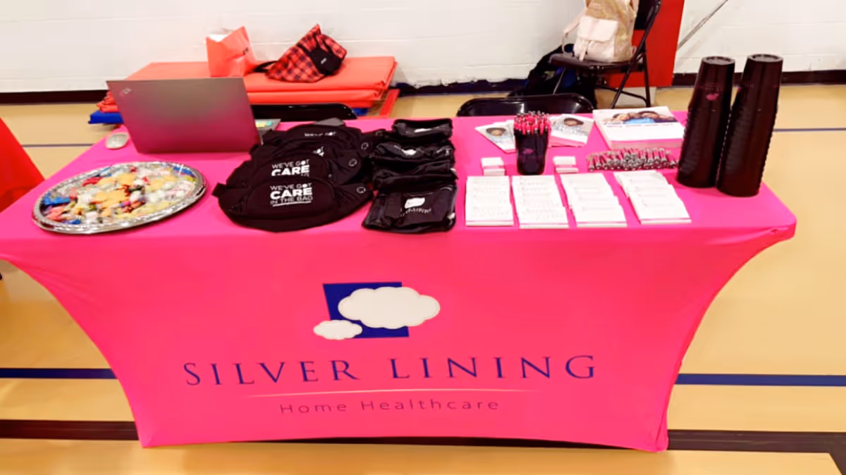 Promotional display on a bright pink tablecloth for Silver Lining Home Healthcare inside gym.