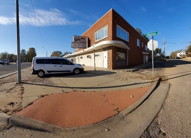 Exterior of Gametime Living LLC building at a street corner with a white van parked.