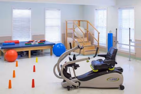 Rehab exercise room with a stationary bike, cones, and therapy equipment.