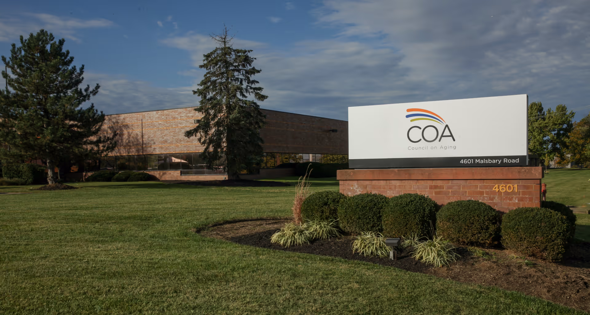 Exterior view of a Council On Aging building with a large sign and landscaped lawn.
