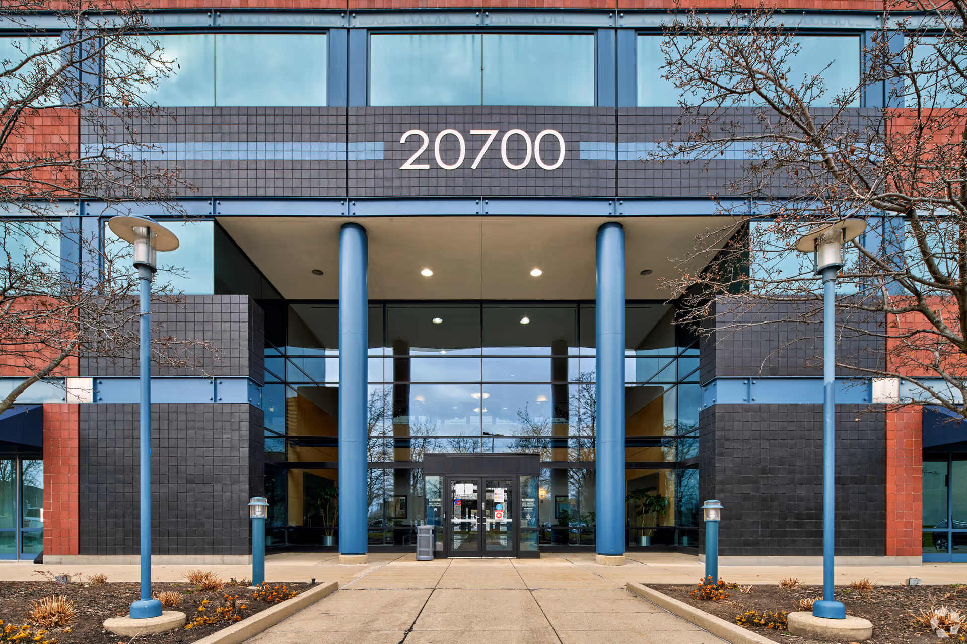 Modern building entrance with blue columns and large glass doors, numbered 20700.