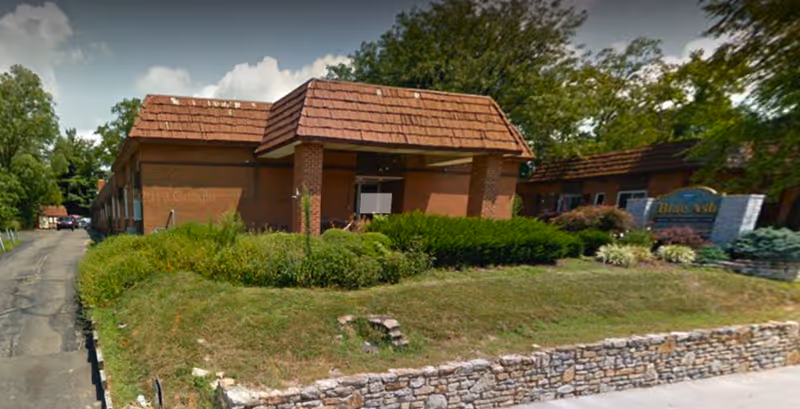 Exterior view of Blue Ash Care Center, brick building with landscaped lawn and sign.