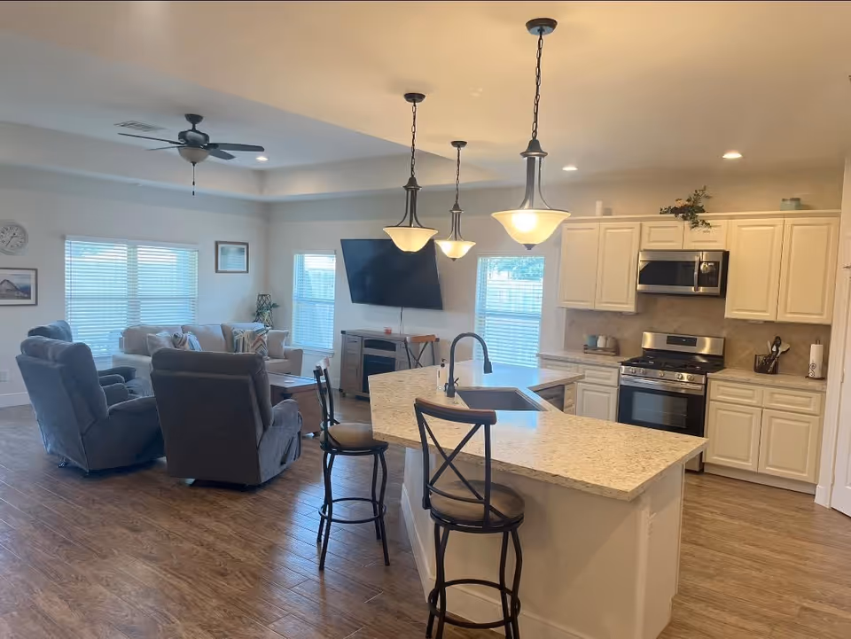 Open-concept living area with kitchen island, bar stools, and a wall-mounted TV.