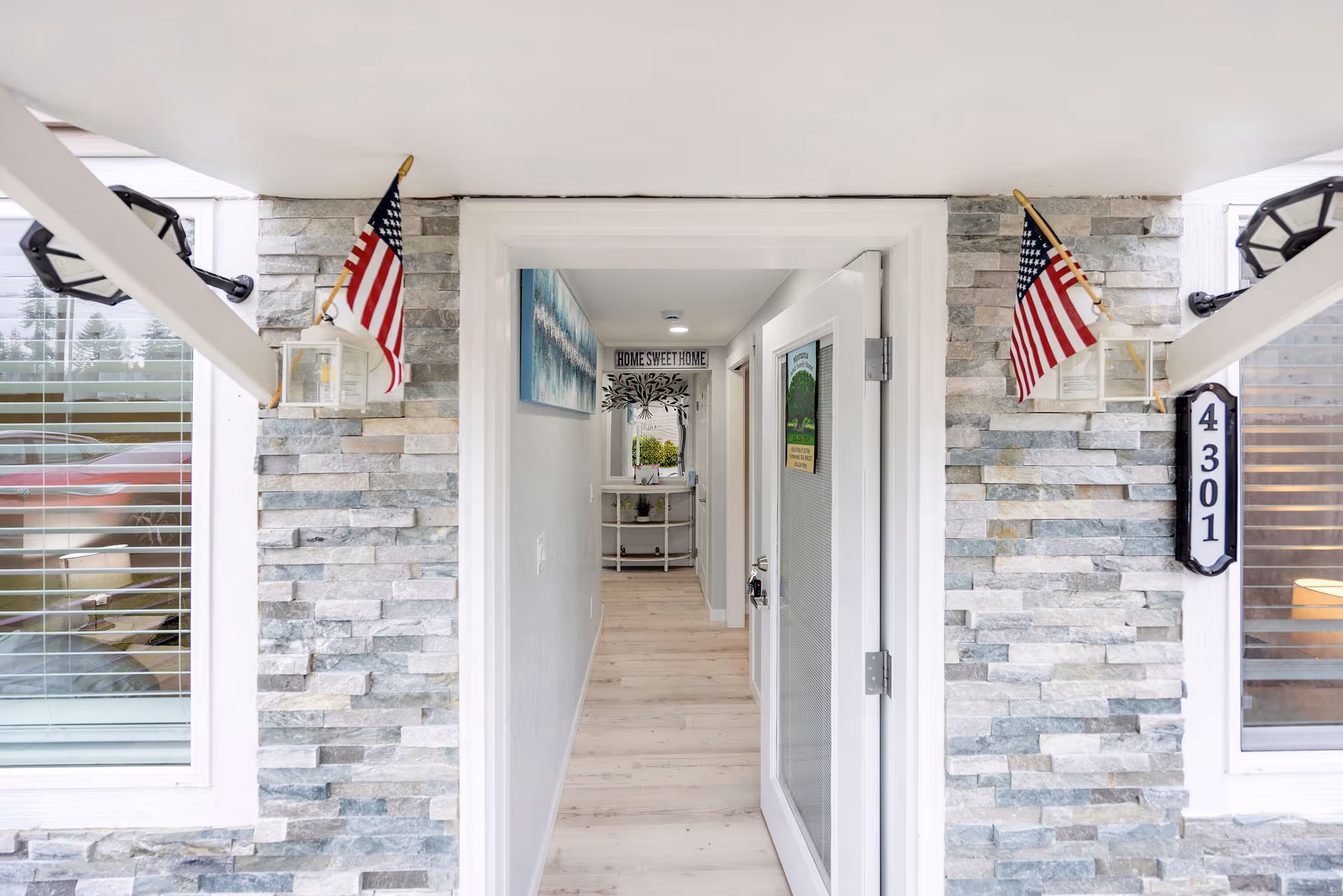 Front entrance with stone walls and American flags leads into a bright interior hallway.