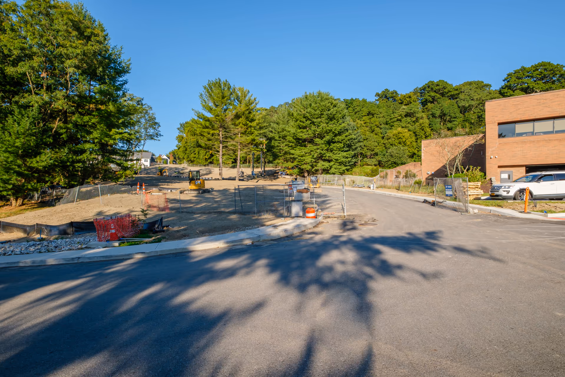 View of a partially constructed area with trees and construction equipment near a building.