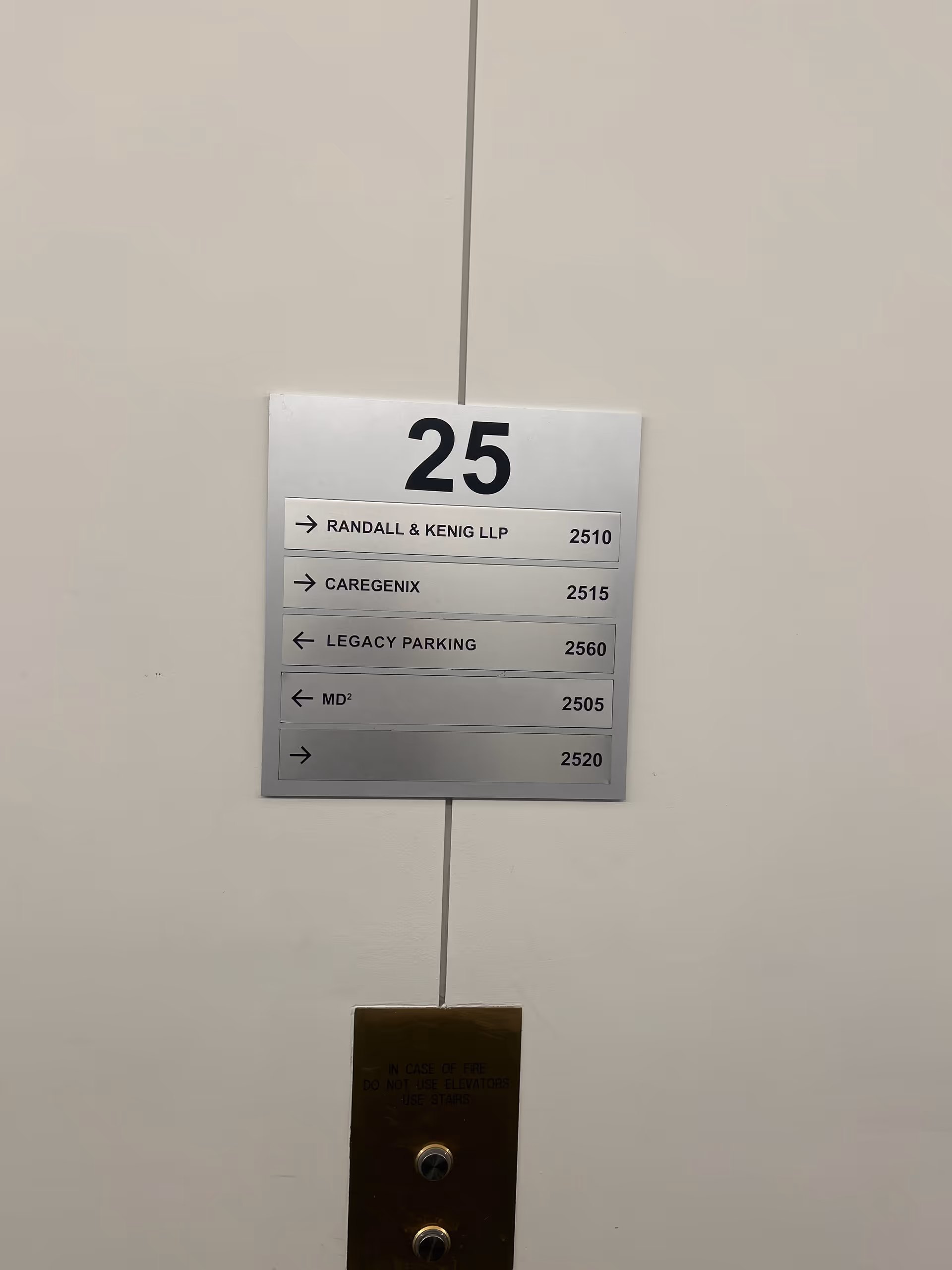 Metal wall sign at floor 25 listing offices including Caregenix.