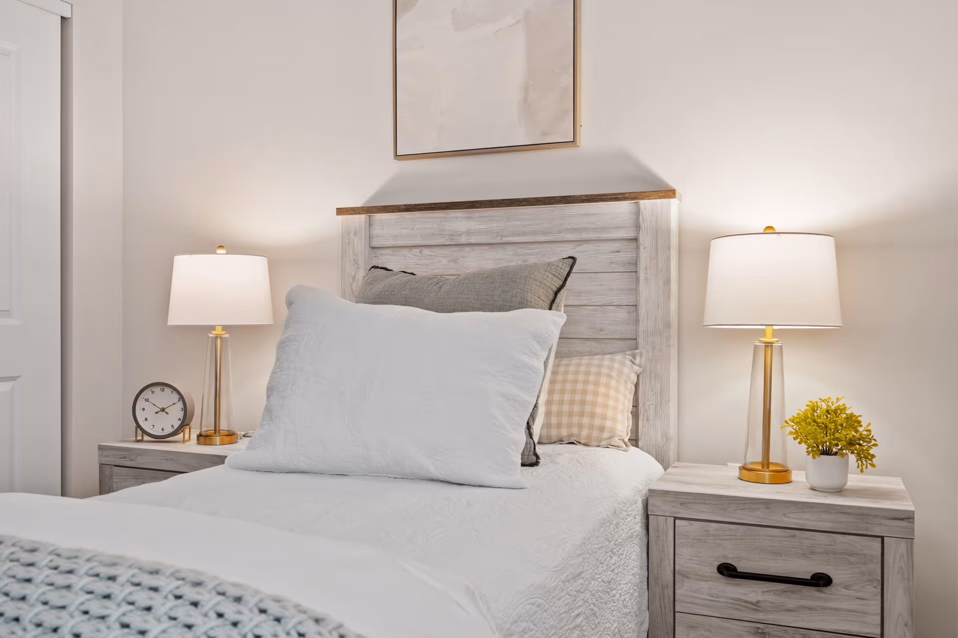A bright, neatly made bedroom with two bedside tables, lamps, and a headboard.