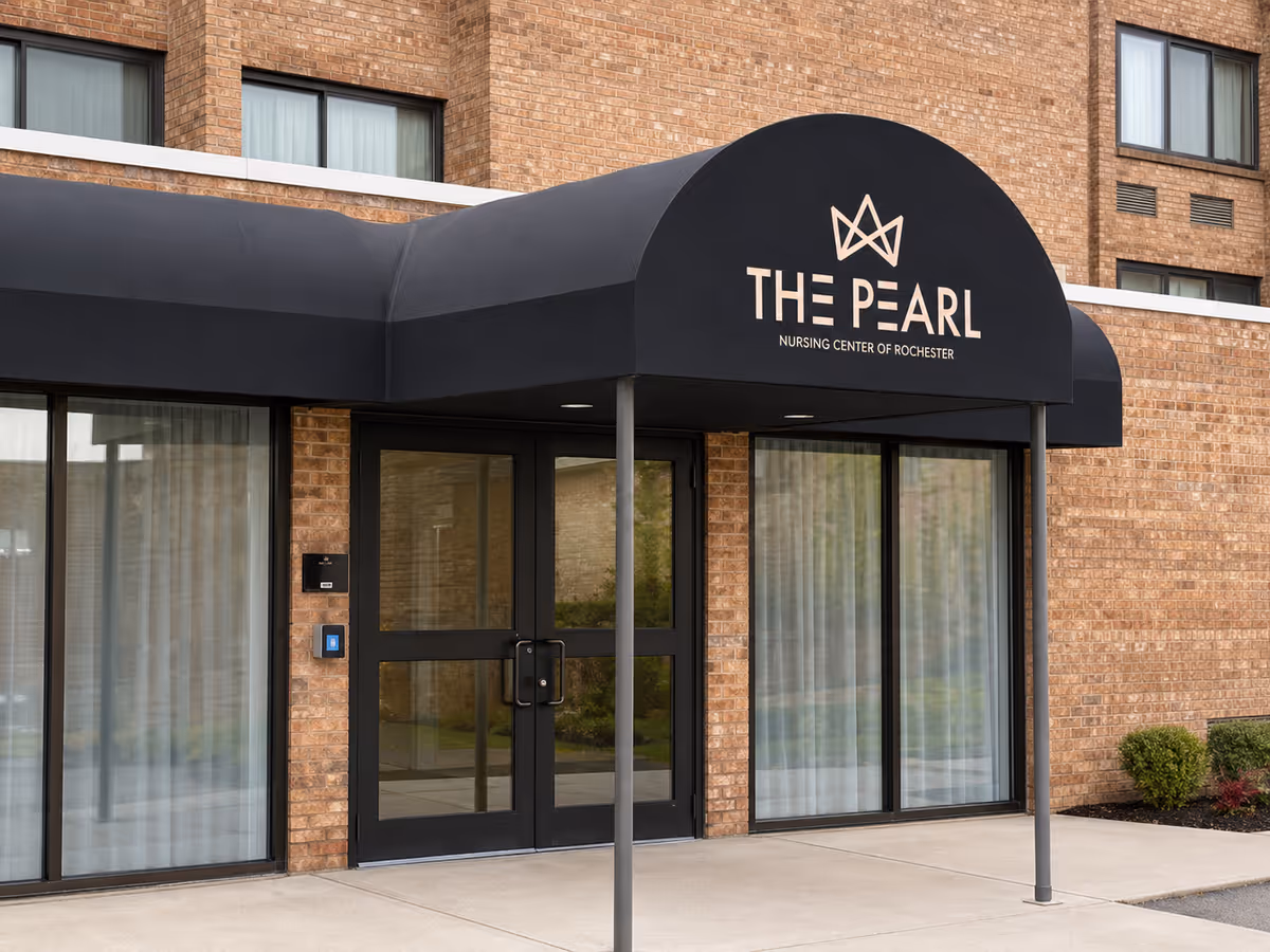 Brick nursing center exterior with a black awning over glass doors reading The Pearl.