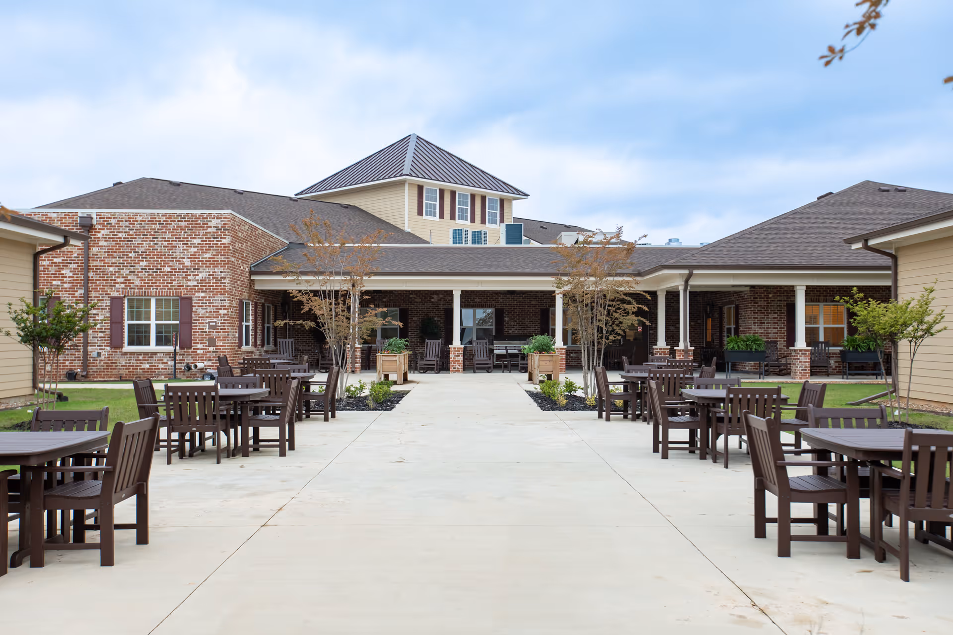 Outdoor courtyard with brick building, covered patio, and numerous tables.
