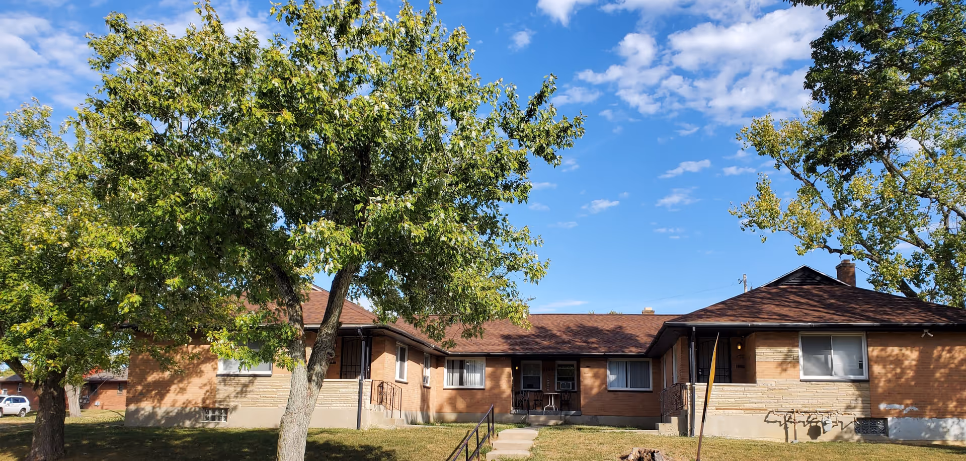 Single-story brick facility with red roof, trees, and blue sky.