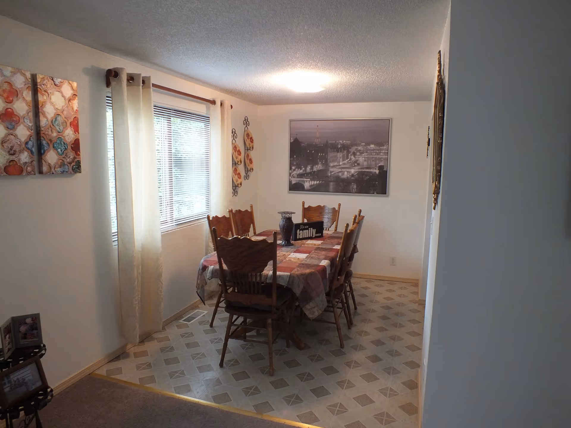 Dining room in a senior facility featuring a table, chairs, curtains, and wall art.