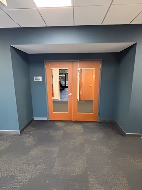 Interior hallway with double wooden doors and teal walls.