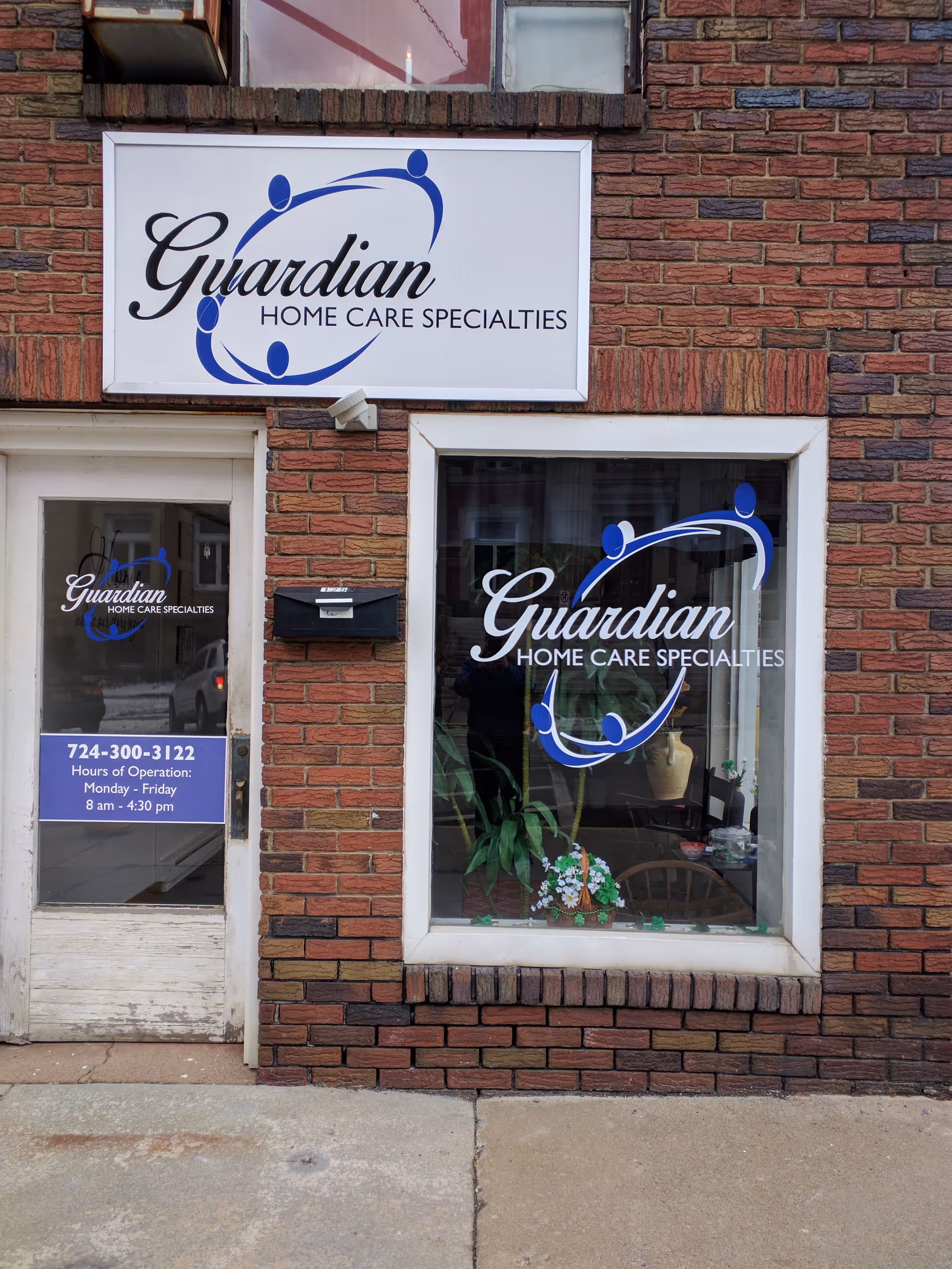 Brick storefront displaying Guardian Home Care signage and logo graphics in windows.