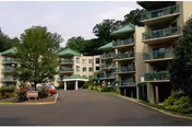 Exterior view of a multi-story senior living facility with balconies and a curved driveway.