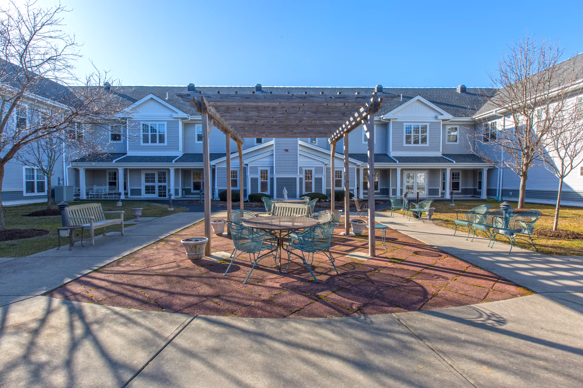 Exterior courtyard of Brookdale Cape Cod featuring a pergola and metal outdoor seating.