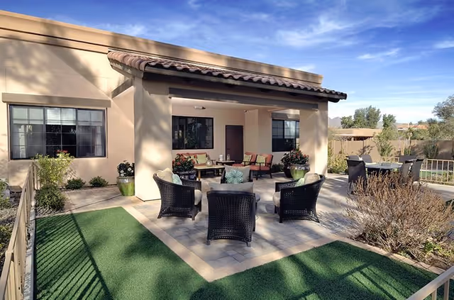 Outdoor patio with wicker seating, potted plants, and a covered seating area.