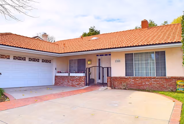 Residential care facility exterior with a gated entrance, brick accents, and a two-car garage.
