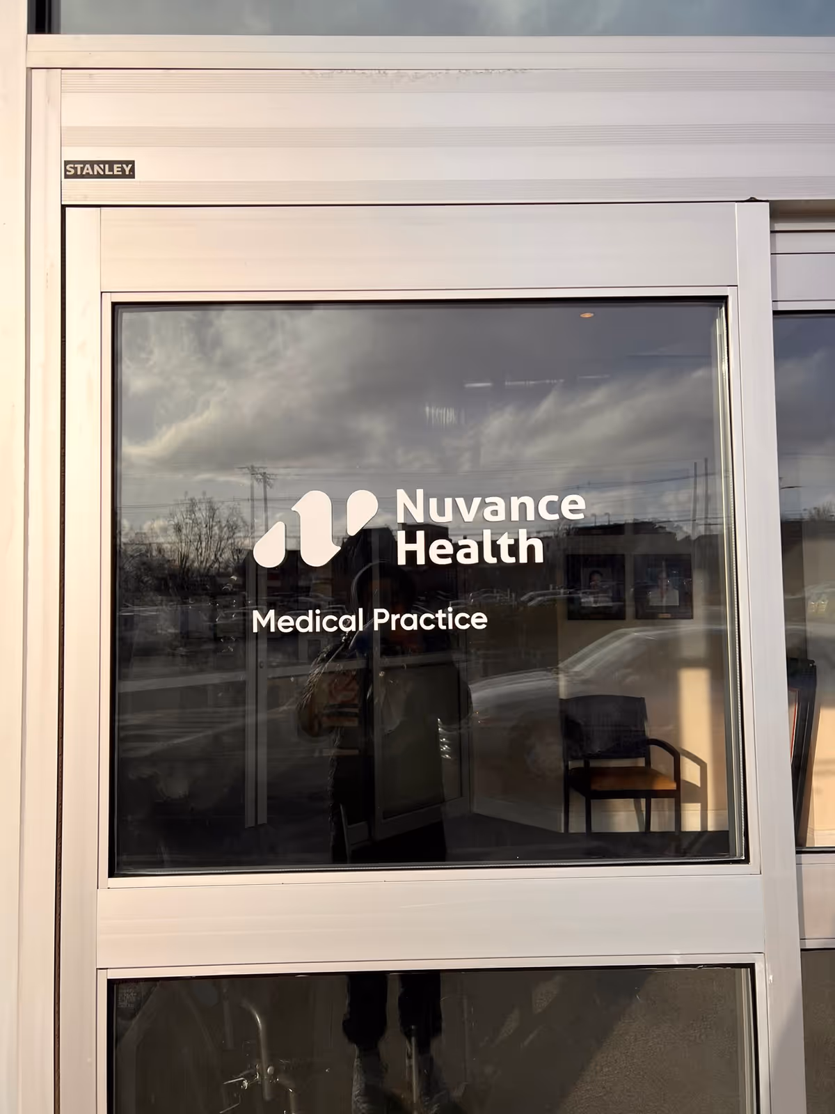 Glass entrance window displays Nuvance Health Medical Practice sign with interior chair visible.