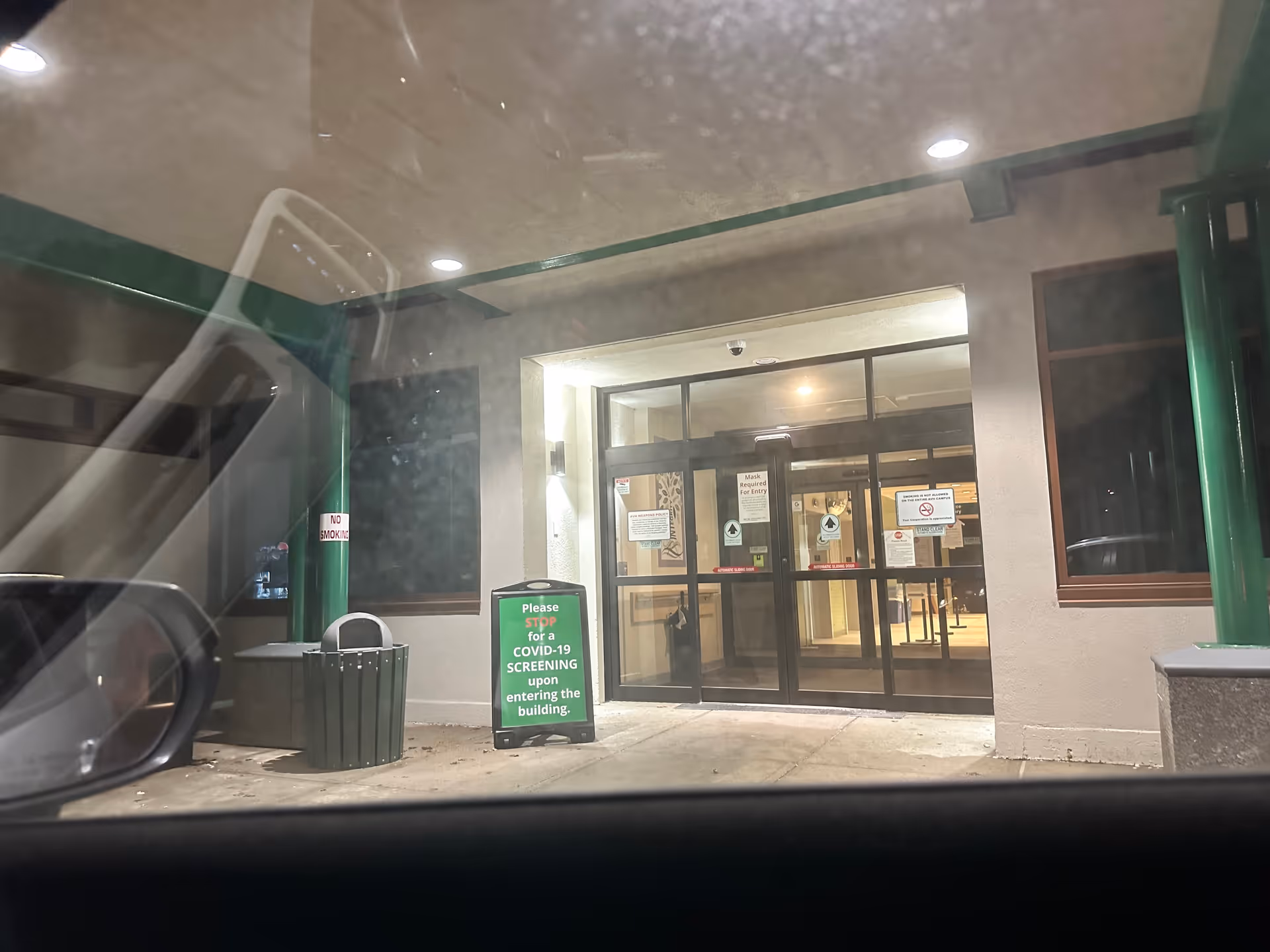 Androscoggin Valley Hospital entrance with glass doors and COVID screening sign.