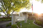 Entrance to Life Care Center of Boise with sign, flag, and landscaped grounds.