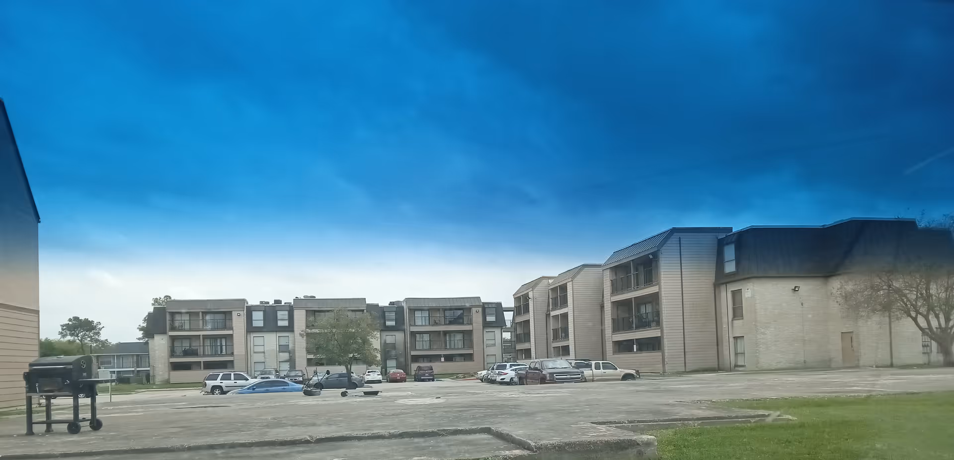 Exterior view of a senior living complex with parked cars and a blue sky.