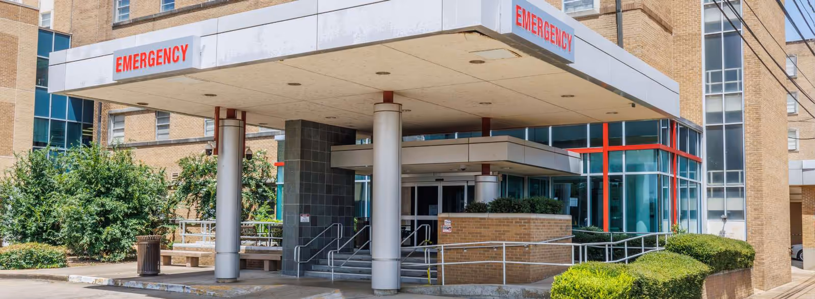 Hospital building exterior with an emergency entrance and ramp access.