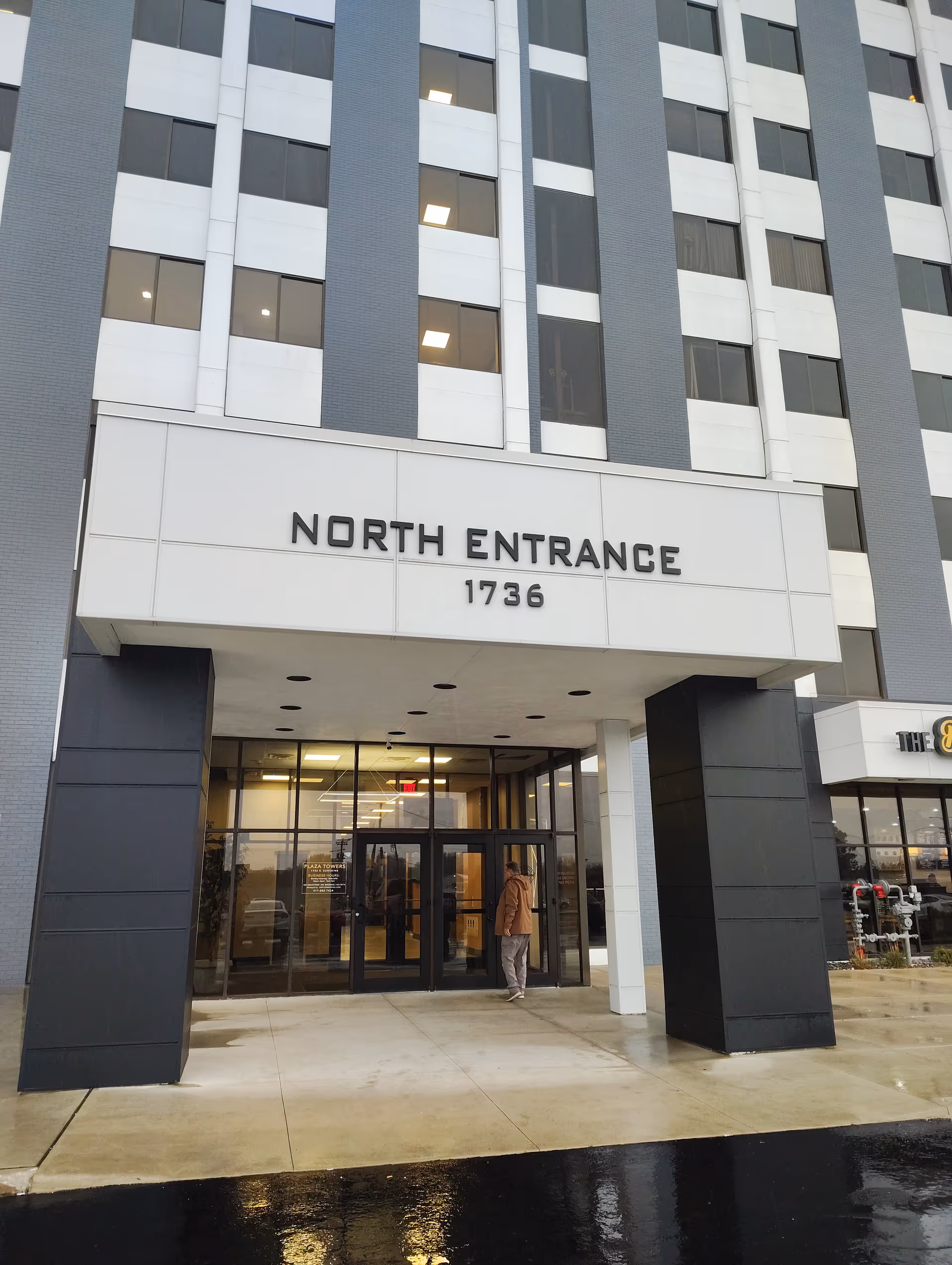 Exterior of a multi-story facility showing the North Entrance and glass doors.