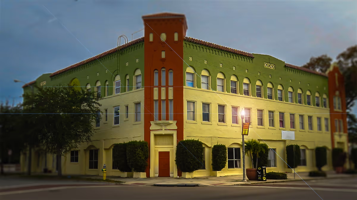 Colorful two-story assisted living building with green upper walls, red towers, and arched windows.