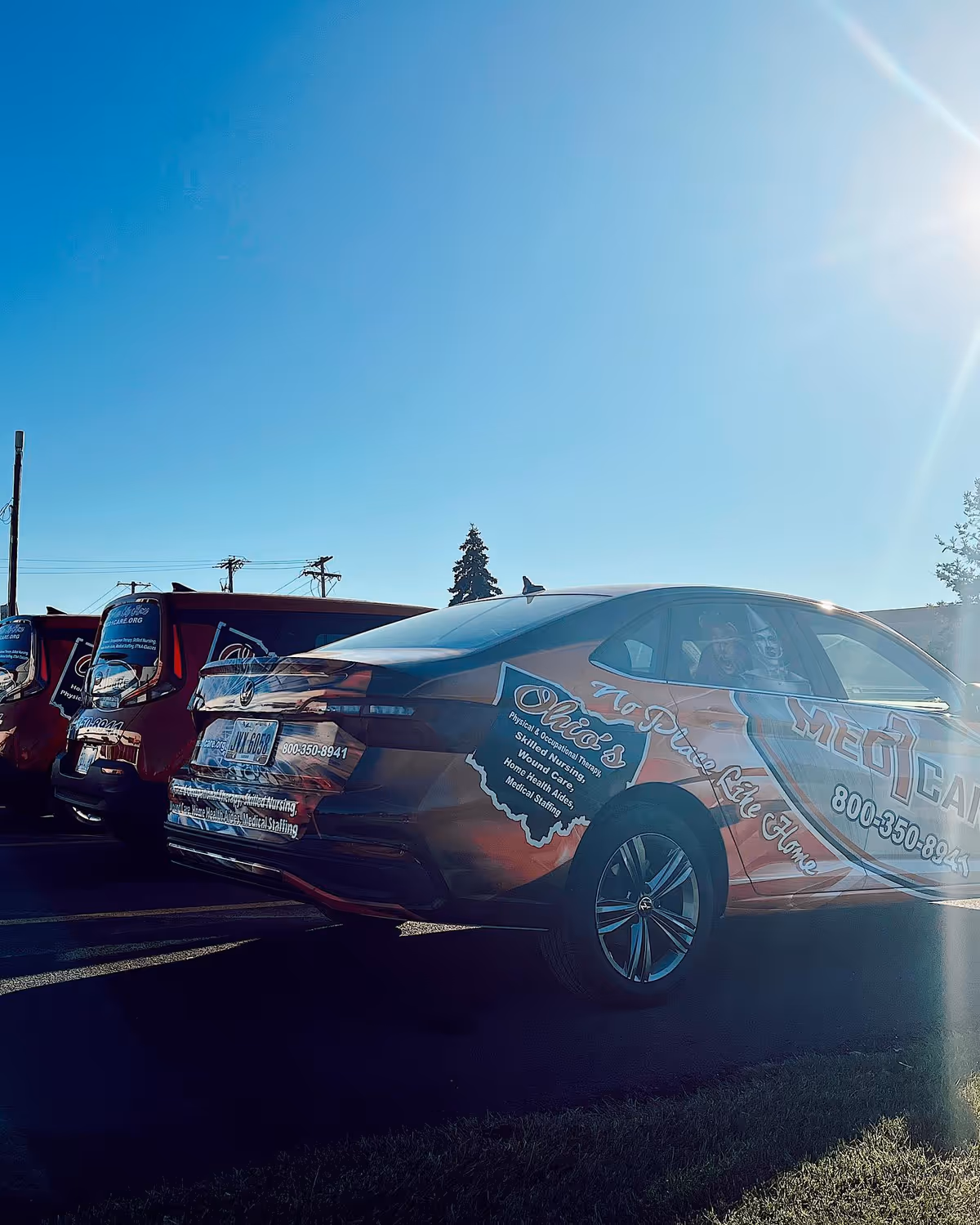 Sunny day parking lot with branded Med1Care vans lined up.