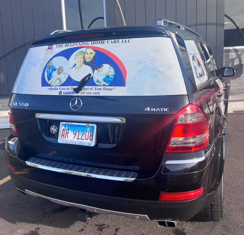 Rear view of a black Mercedes SUV with The Beginning Home Care wrap.
