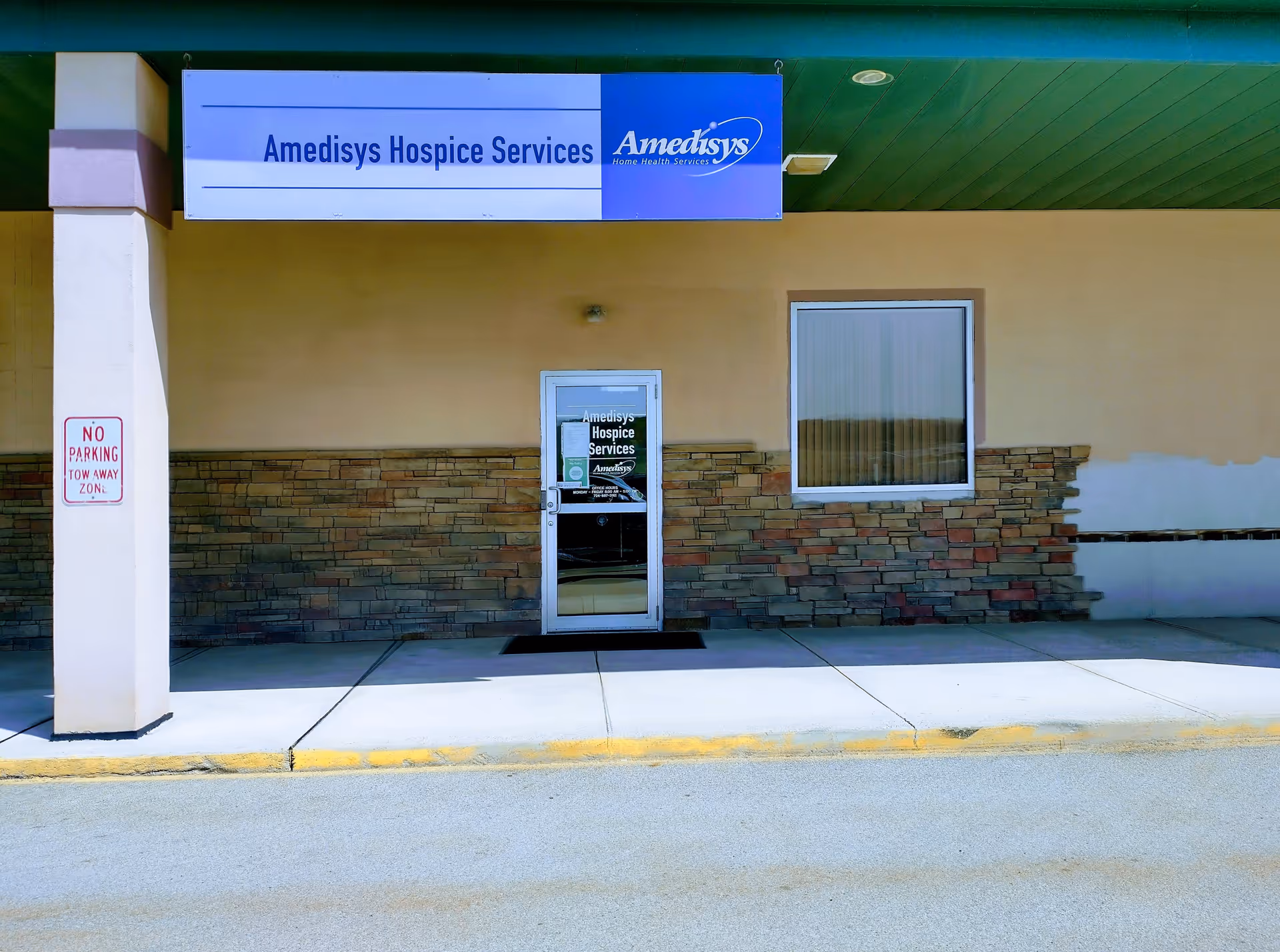 Amedisys Hospice Services entrance with blue-and-white sign over a brick facade.