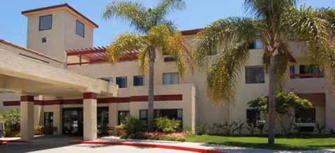 Beige Brookdale Irvine building exterior with palm trees and a covered entrance