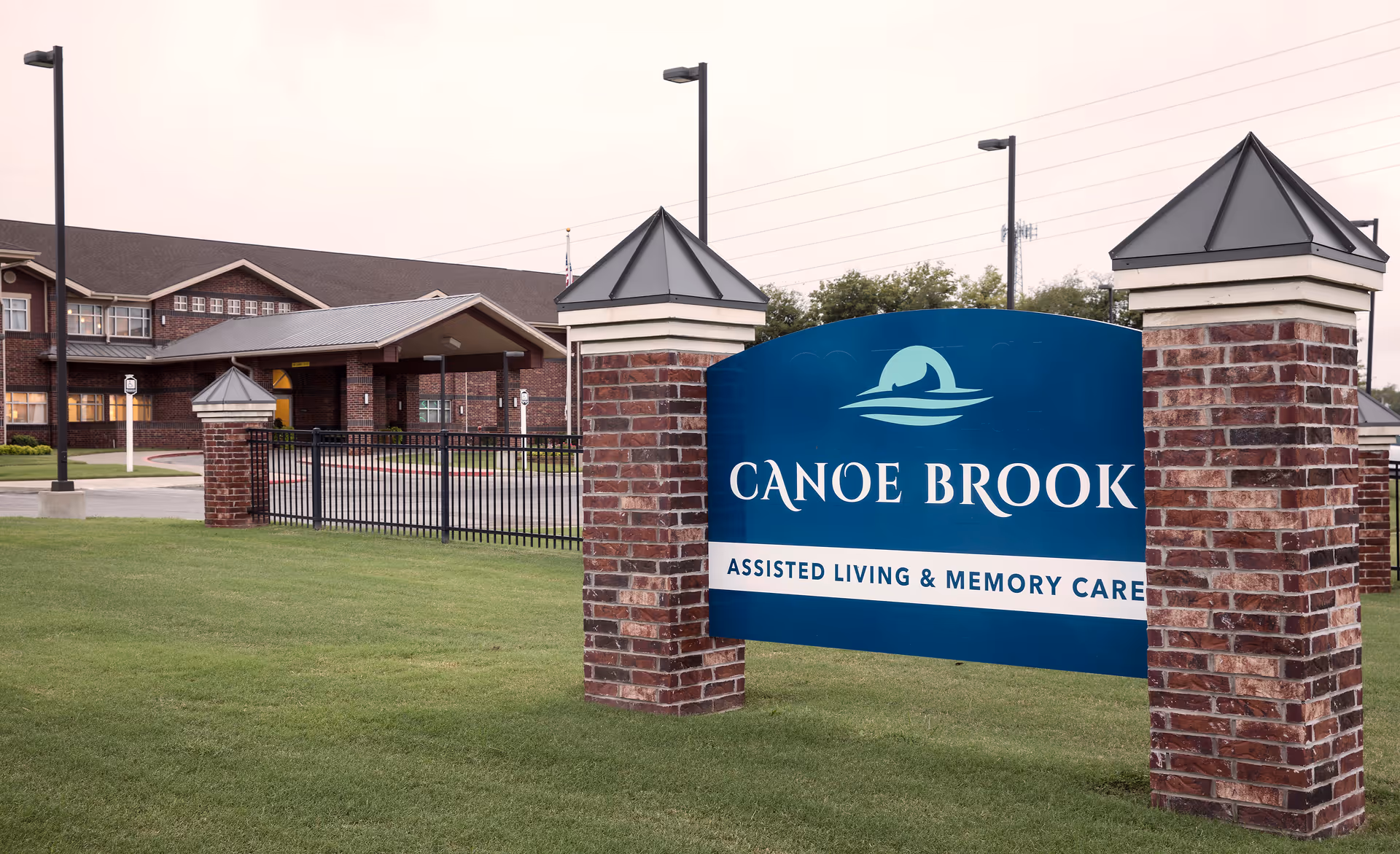 Blue Canoe Brook sign with Assisted Living & Memory Care text between brick pillars.