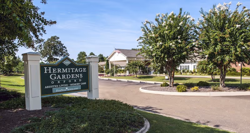Exterior view of an assisted living facility with a sign and circular driveway