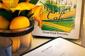 Close-up of lemons on a counter with a cafe sign in an interior dining area.