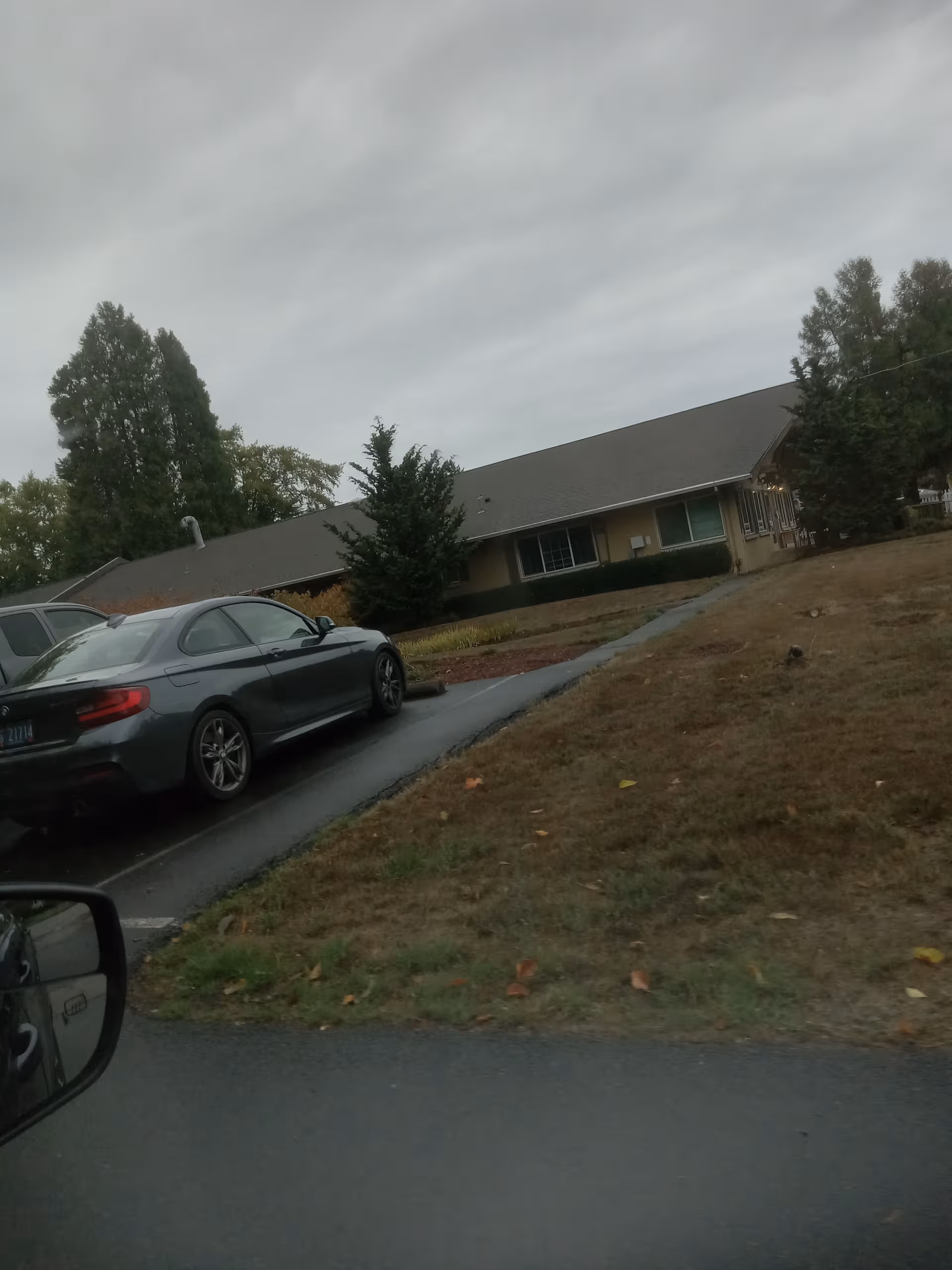 Single-story senior living facility exterior with parked cars along the driveway.