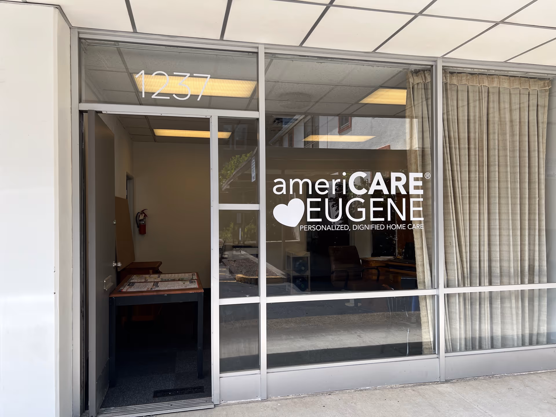 Glass storefront entrance with ameriCARE Eugene sign and visible office interior
