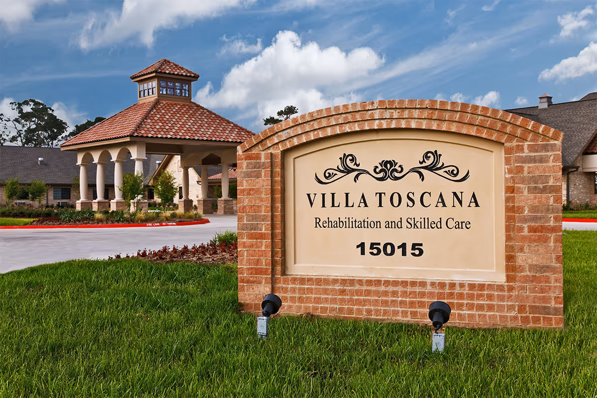 Brick sign reads Villa Toscana Rehabilitation and Skilled Care with a building entrance and lawn.
