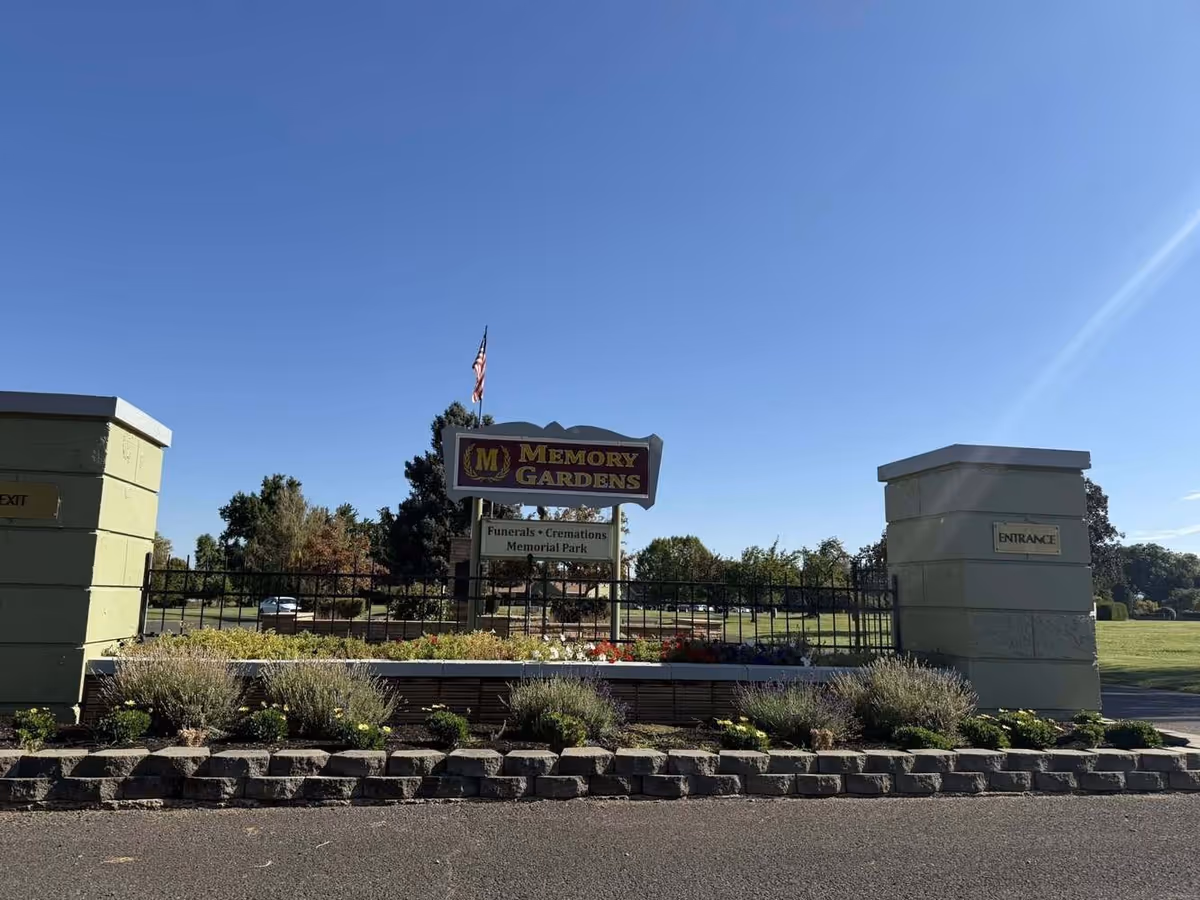 Exterior entrance to Memory Gardens senior living with landscaped grounds and gate.