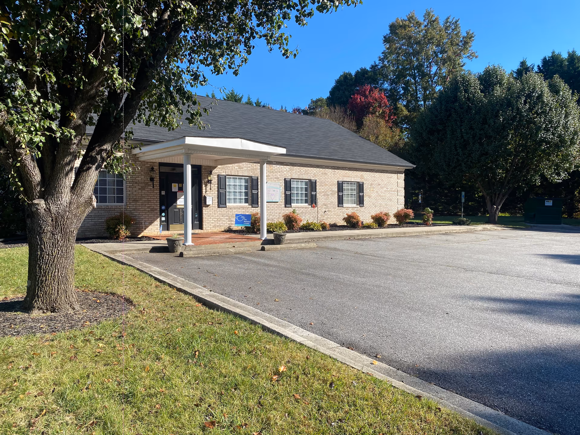 Brick senior living facility with a covered entrance and nearby parking.