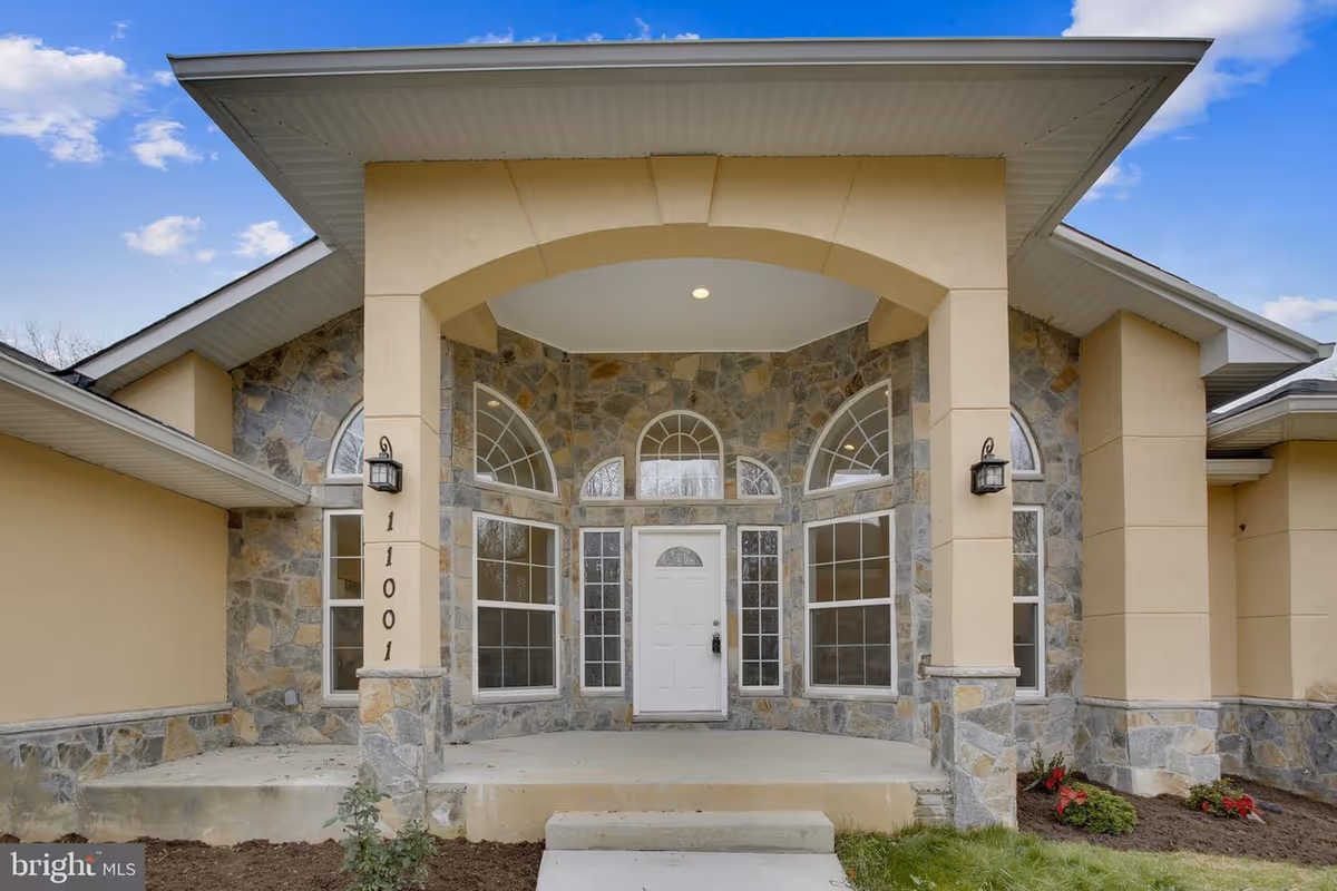 Front entrance of a stone-and-stucco building with arched windows and a covered porch.