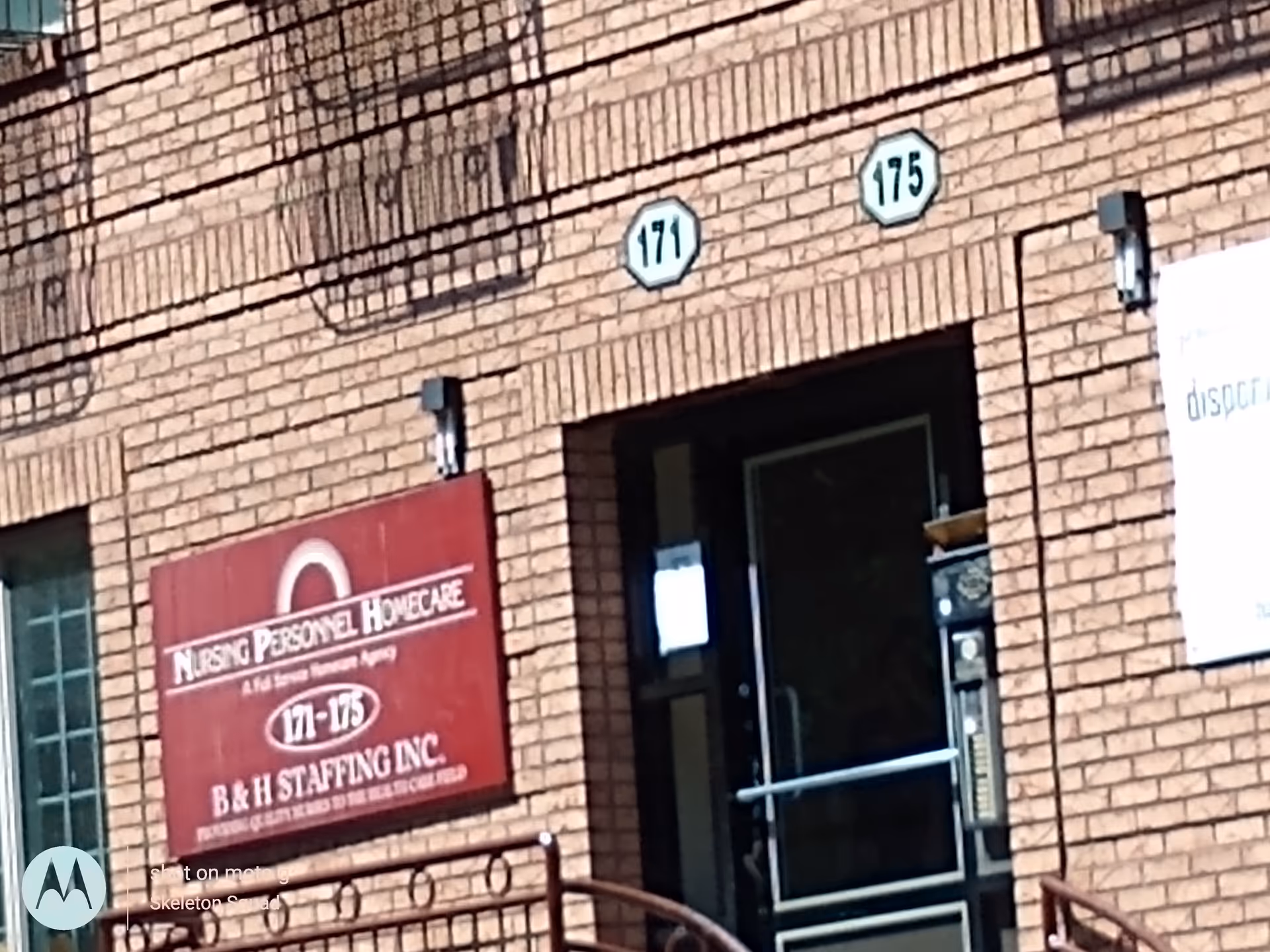Brick building entrance with a red Nursing Personnel Homecare sign and address numbers.